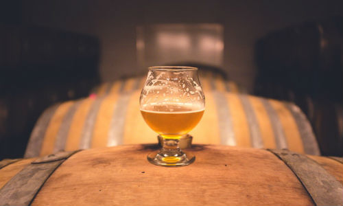 Is that craft beer really an indie? Craft brewers hope to distinguish themselves from bigger brewers by declaring their ownership on the bottle. ("Focus Photography of Footed Glass Half Full" photo courtesy of Pexels).