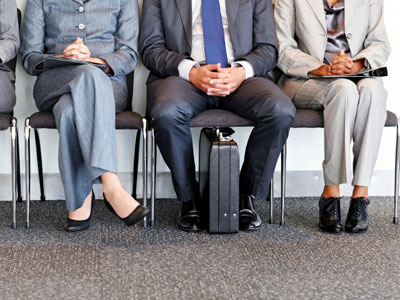 Three people sitting next to each other in an interview waiting room