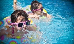 two little girls wearing sunglasses in a swimming pool