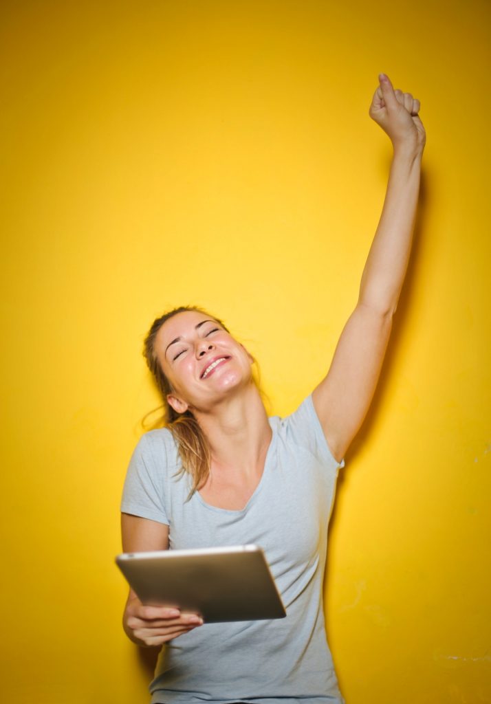 Woman holding an arm up high with a smile, celebrating success