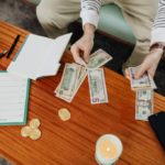 man sitting at coffee table counting money with budgeting