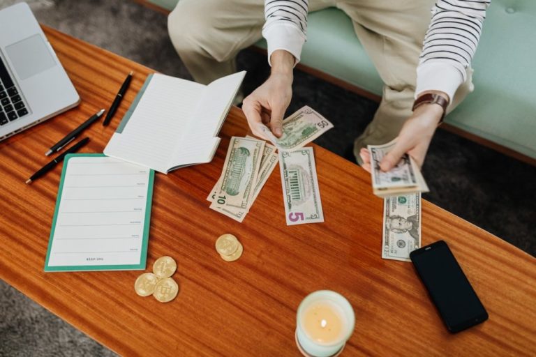 man sitting at coffee table counting money with budgeting