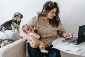woman holding newborn wile working on laptop computer