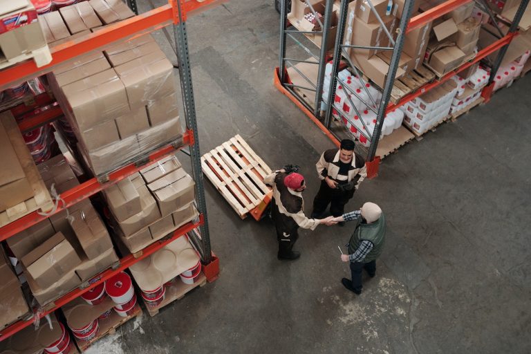Three men in warehouse, two shaking hands