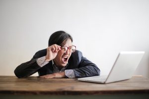 Man with glasses in suit yelling at computer screen