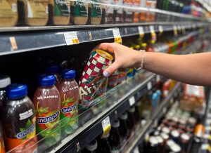 Person grabbing an Arizona Iced Tea off the supermarket shelf