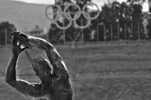 Statue of disc thrower with Olympic rings in the background