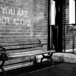 Empty bench in front of brick wall