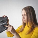 Woman looking into empty wallet frustrated