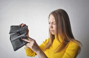 Woman looking into empty wallet frustrated