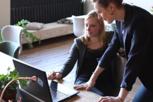 Two women in business attire looking at a computer