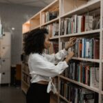 woman looking through library bookshelves