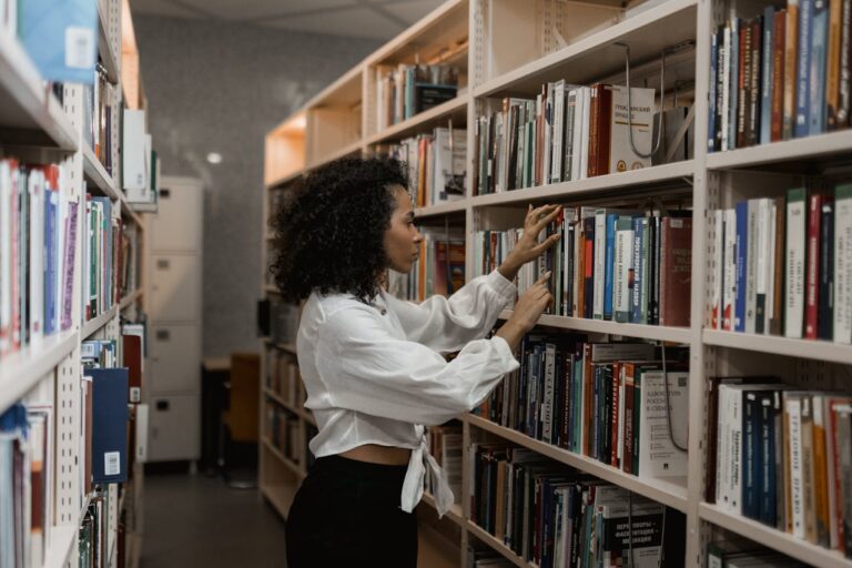 woman looking through library bookshelves