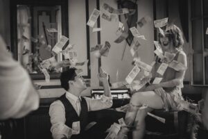 Couple by piano among flying money in twenties clothing