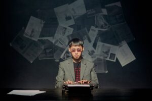 Man in gray suit typing on typewriter in dark room