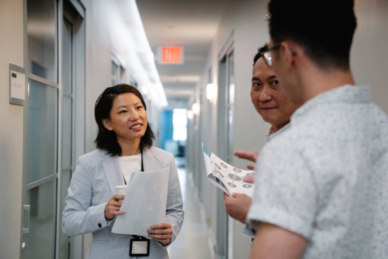 Woman in Striped Blazer Listening to Two Men in the Hallway