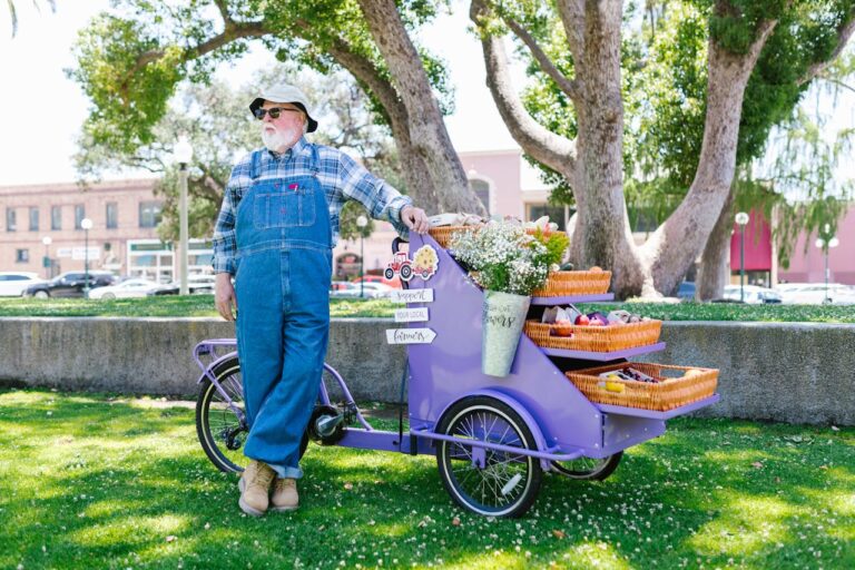 An elderly man in denim jumper standing near his cart