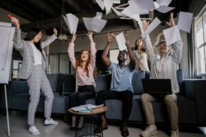 Group of coworkers throwing pieces of paper in the air in celebration