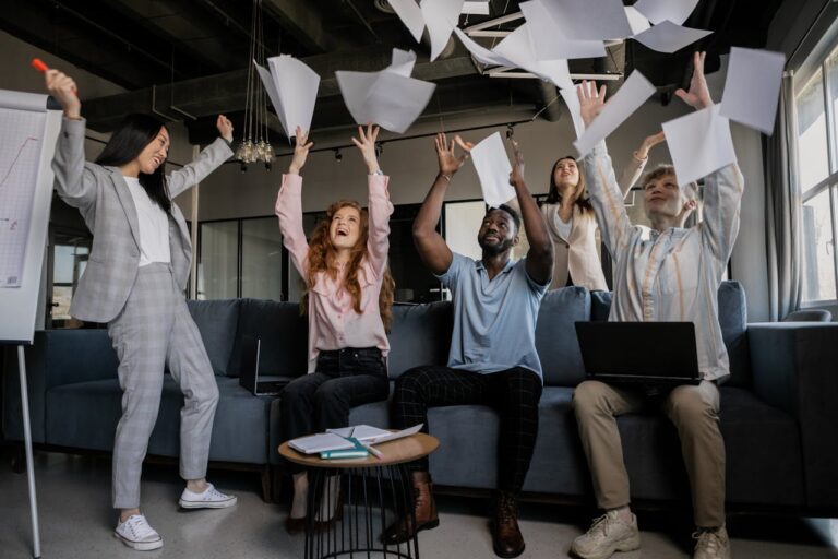 Group of coworkers throwing pieces of paper in the air in celebration