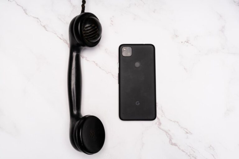 Black Cellphone Beside a Black Telephone Receiver