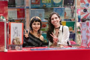 Two women smiling behind an artist booth