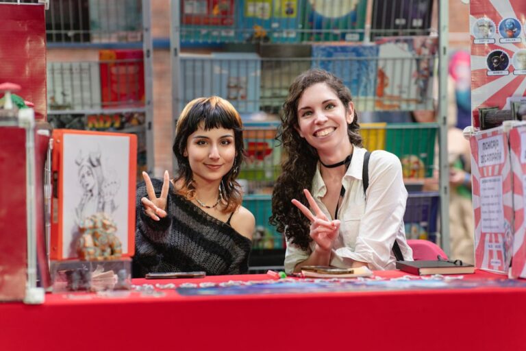Two women smiling behind an artist booth