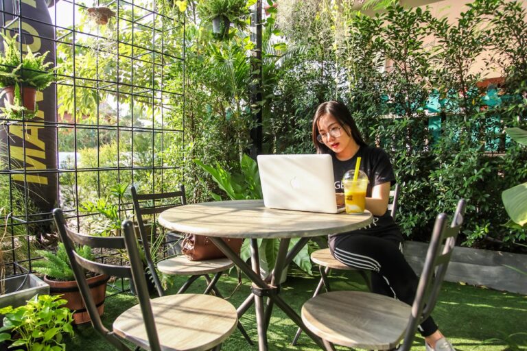 Woman using laptop on table in green garden