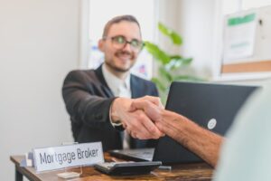 Mortgage broker shaking hand with person sitting across desk