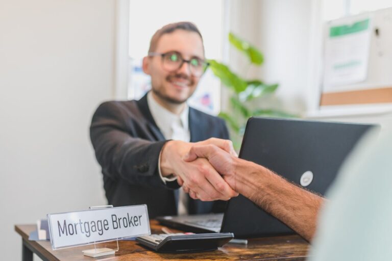 Mortgage broker shaking hand with person sitting across desk