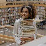 Woman carrying stack of books and smiling