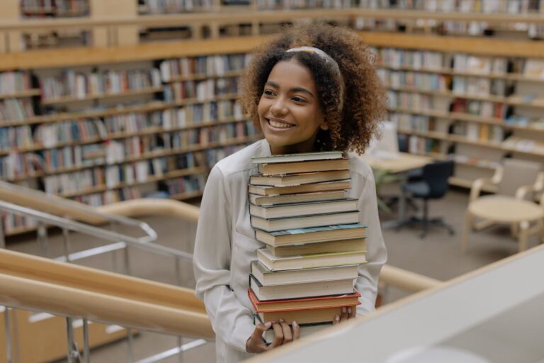 Woman carrying stack of books and smiling
