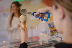 Woman scooping ice cream onto cone for customer