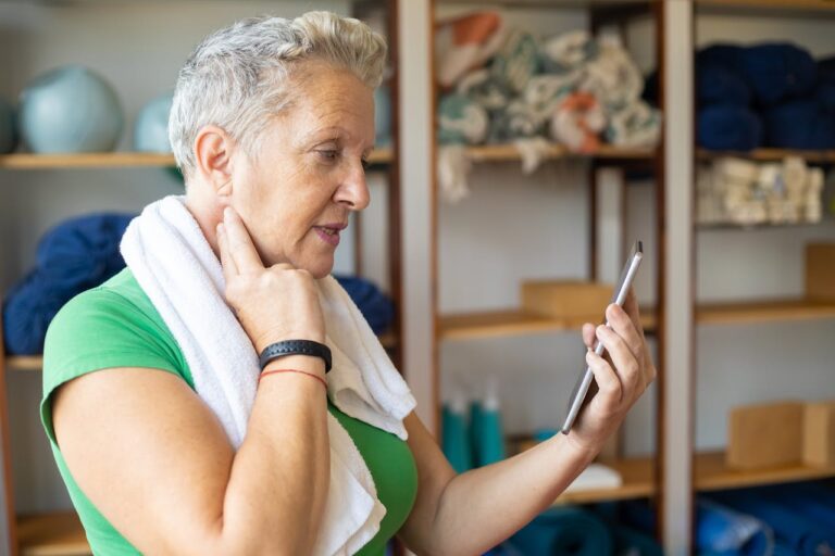 Woman looking at device while checking her own pulse