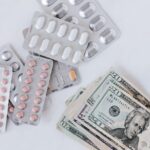 Different pill blisters near pile of American dollar banknotes
