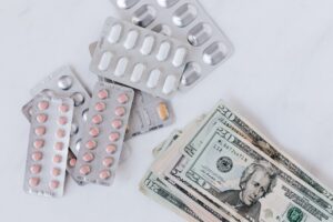 Different pill blisters near pile of American dollar banknotes