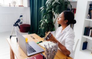 women sitting at desk with computer demonstrating a chart to a phone camera