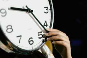 A hand moves the hand on a clock for daylight saving time