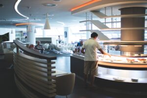 Man in white collared top getting food at a airport lounge
