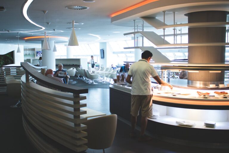 Man in white collared top getting food at a airport lounge