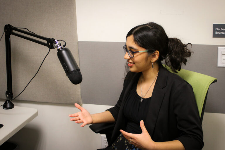 Ananya Bhargava sitting in a chair talking into a podcast microphone