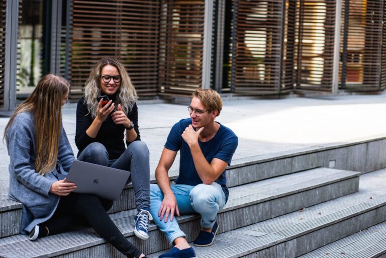Three people Sitting on the Stairs outside Talking With Each Other