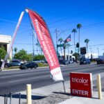 tattered flag outside car dealership near main street with cars