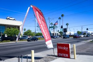 tattered flag outside car dealership near main street with cars