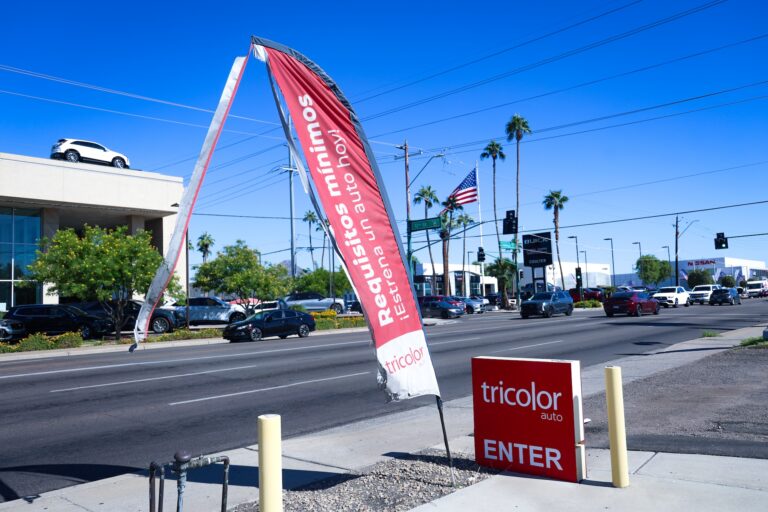 tattered flag outside car dealership near main street with cars