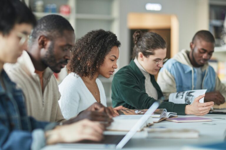 A group of students sit at a table reading