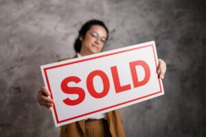 Woman in suit holding "Sold" sign