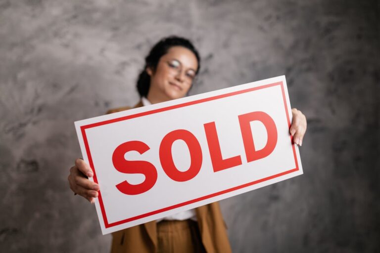 Woman in suit holding "Sold" sign