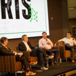 Four men sitting on a stage having a panel discussion