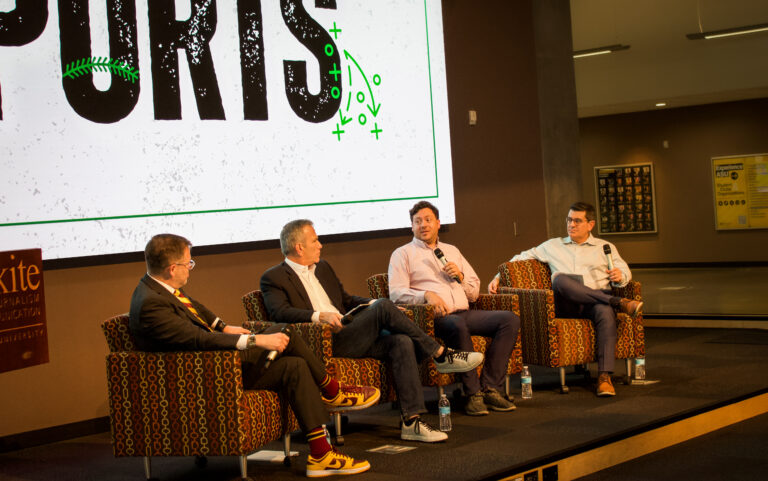 Four men sitting on a stage having a panel discussion