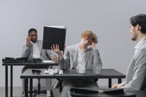 three men in gray suits sitting bored in an office